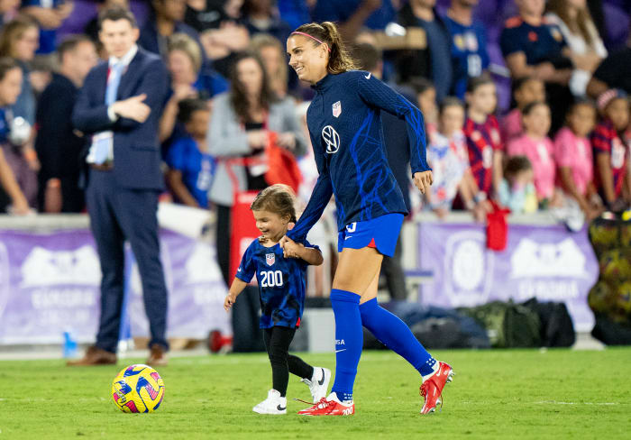 U.S. forward Alex Morgan holds her daughter's hand on the field before a game.